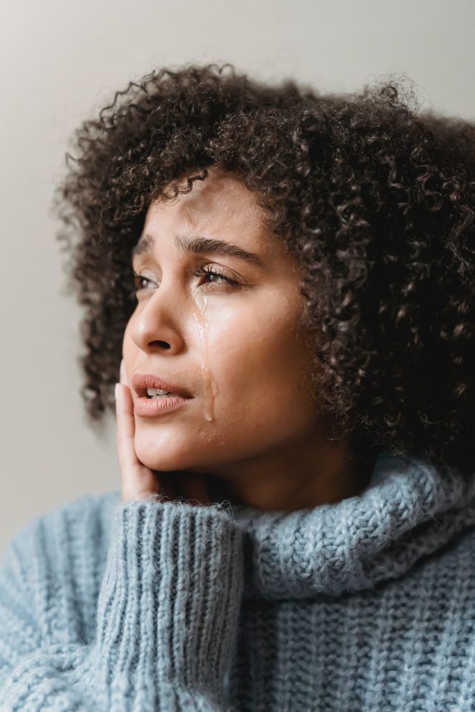 woman crying touching cheeks