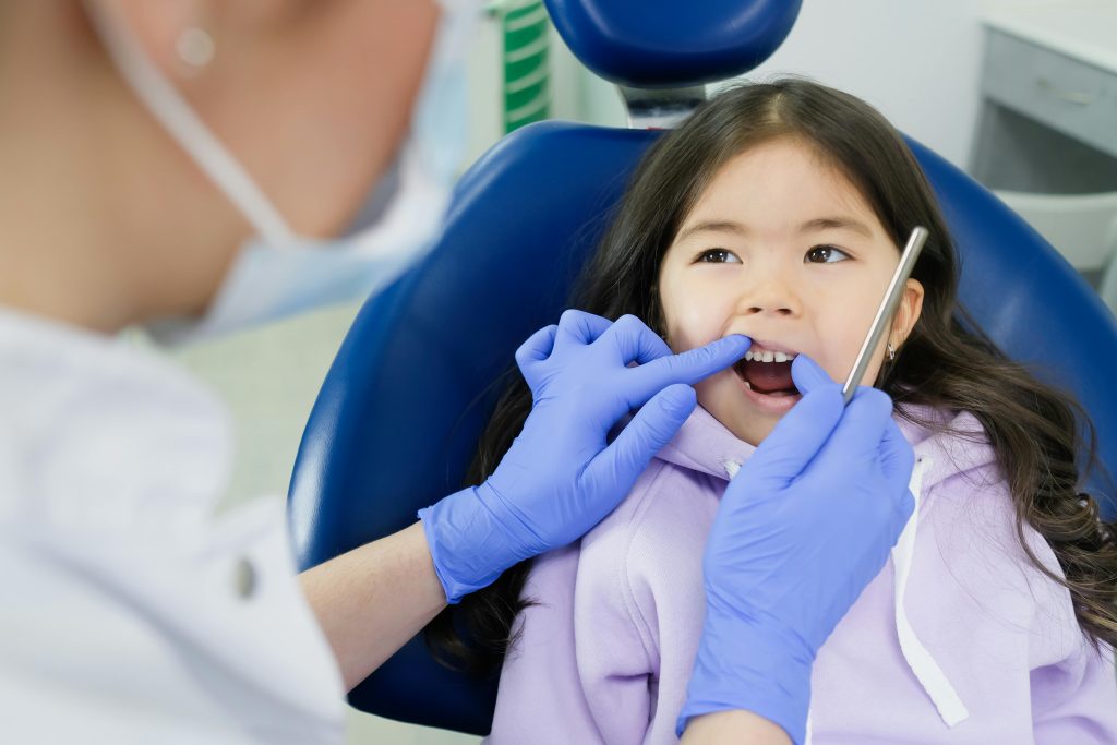 dentist examining a girl's teeth on dental chair