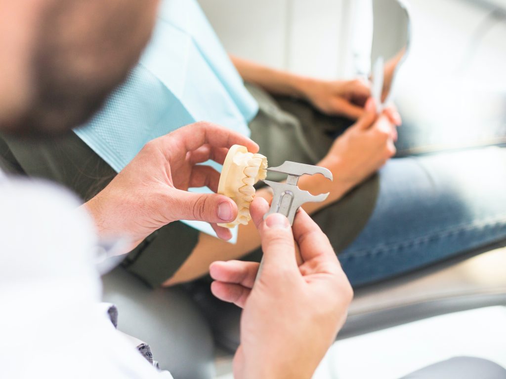 dentist measuring a teeth model using vernier caliper