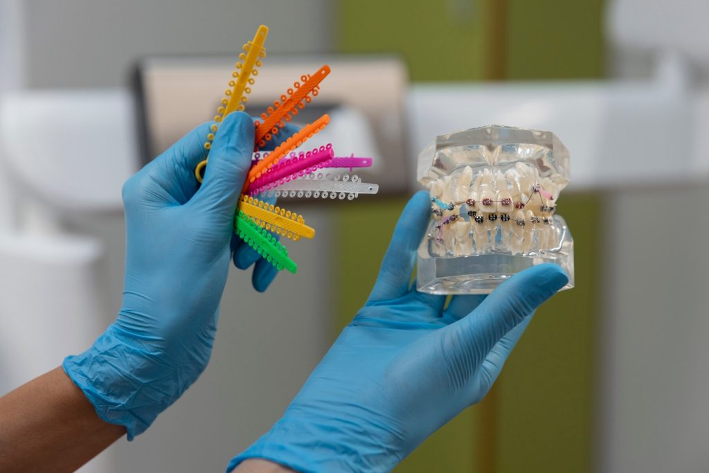 Orthodontist holding colour modules on one hand and braces typodont on another hand