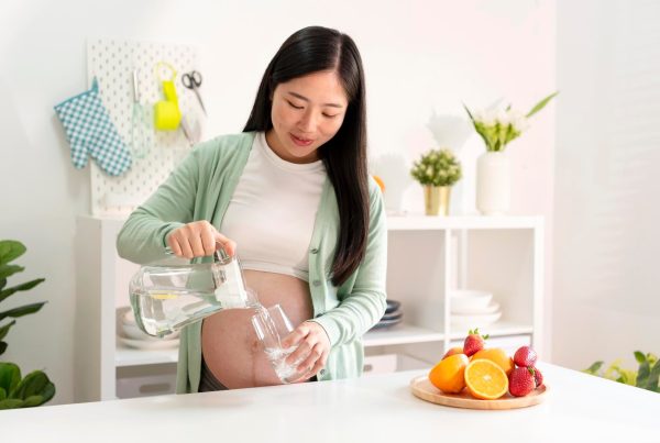 pregnant woman pouring water into a cup inside a kitchen