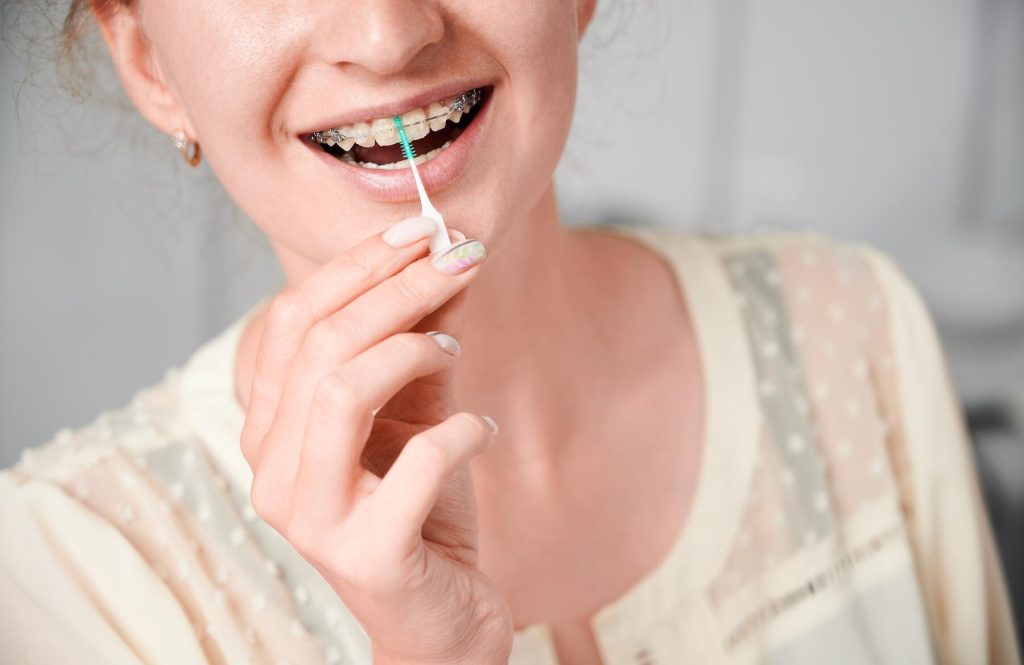 woman with braces using interdental brush